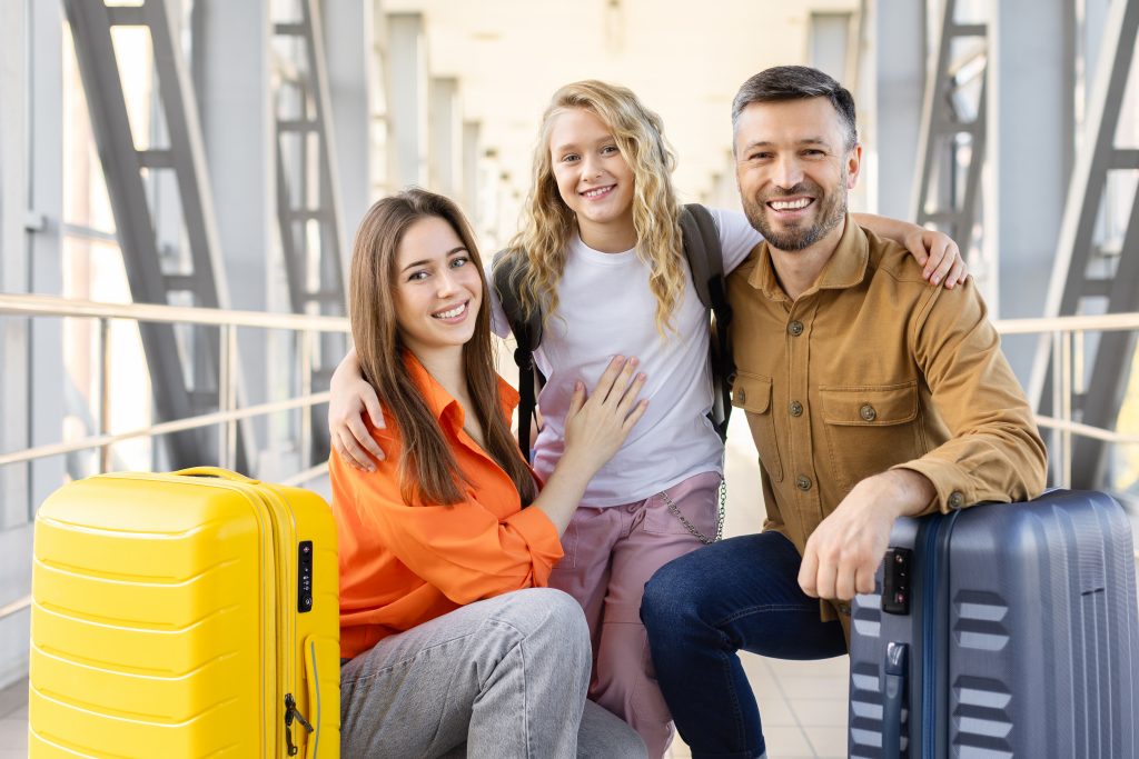 Cheerful family hugging at airport terminal with luggage, enjoying warm moment together before departure on holiday travel and vacation journey