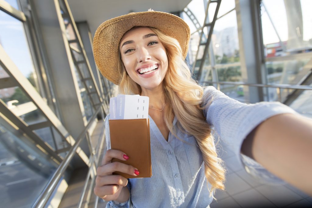 Frau steht am Flughafen mit Reisepass in der Hand