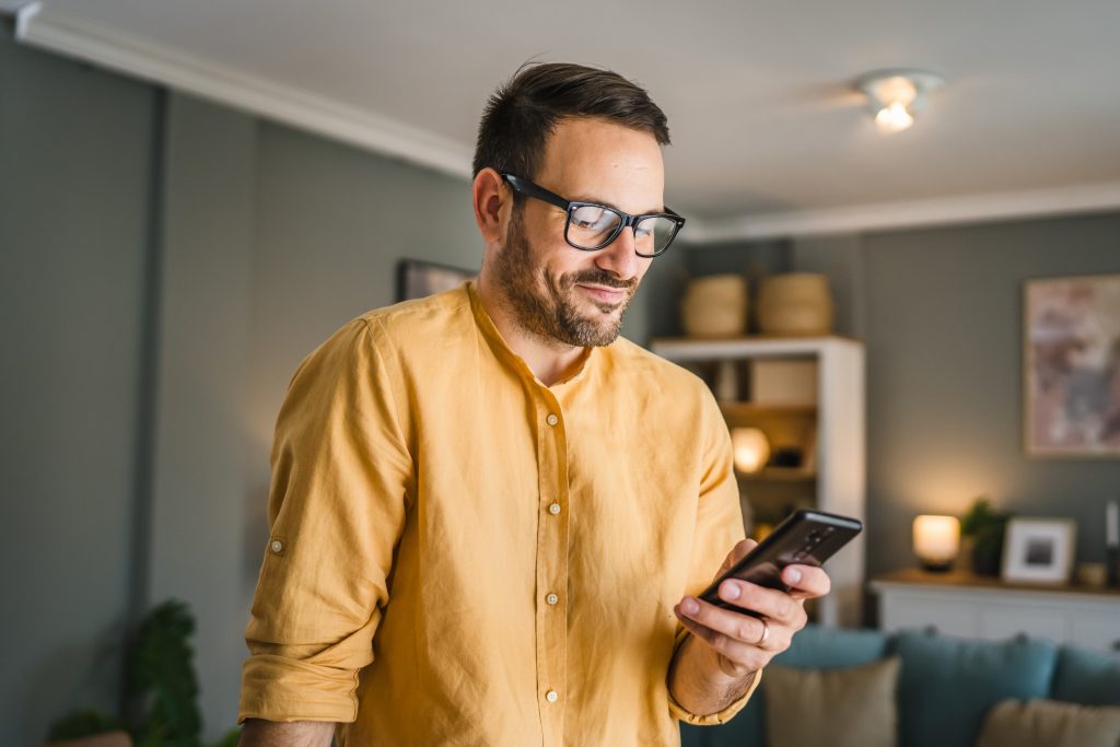 Ein Mann steht mit seinem Smartphone im Bild