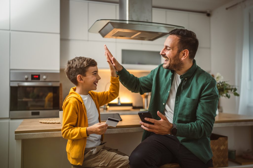 Son and father sit at home buy online on mobile phone with credit card
