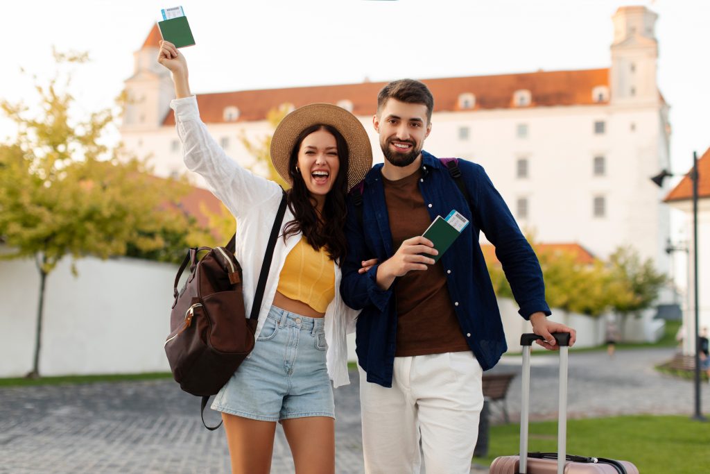 Happy European tourists holding passports and smiling while exploring historic site during their trip